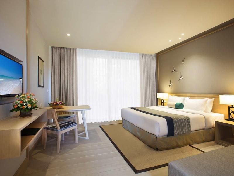 Moderne hotelkamer met groot bed, bureau en vloer-tot-plafond raam met gordijnen.