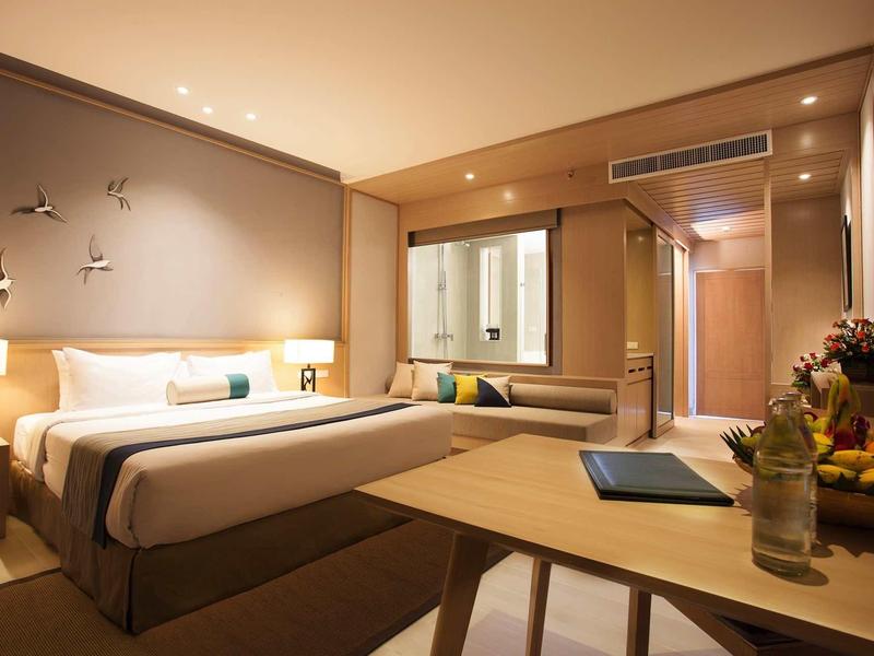 Modern ingerichte hotelkamer met tweepersoonsbed, bureau en groot raam.