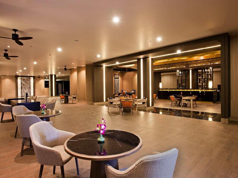 Moderne hotel lounge met ronde tafels en comfortabele stoelen in warm licht.