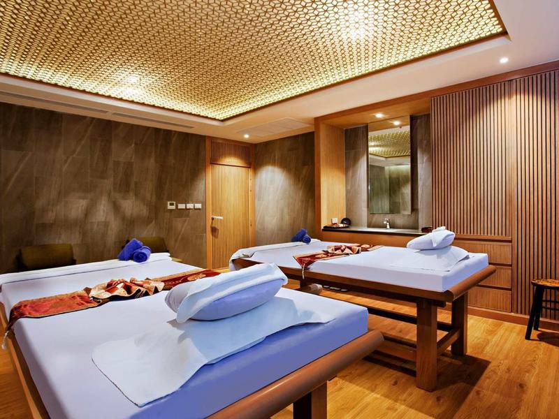 Licht verlichte massageruimte met drie comfortabele behandeltafels en decoratieve houten muren.