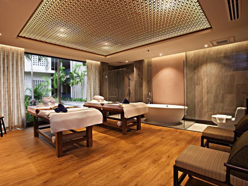 Elegante spa-ruimte met twee massagetafels, badkuip en groot raam met uitzicht op de tuin.