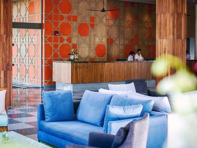 Moderne hotellobby met blauwe banken en licht hout bij de receptie.