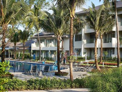 Moderne hotelzwembad met palmbomen en ligstoelen in een tropische tuin.