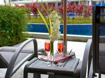 Tafel op terras met twee glazen rosé en bloemdecoratie in hotel tuin.