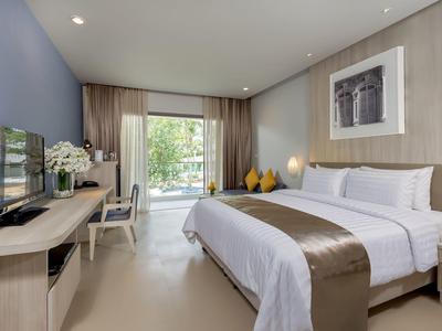 Moderne hotelkamer met groot bed, bureau en uitzicht op een terras.