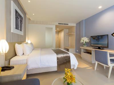 Modern ingericht hotelkamer met tweepersoonsbed, bureau en televisie.