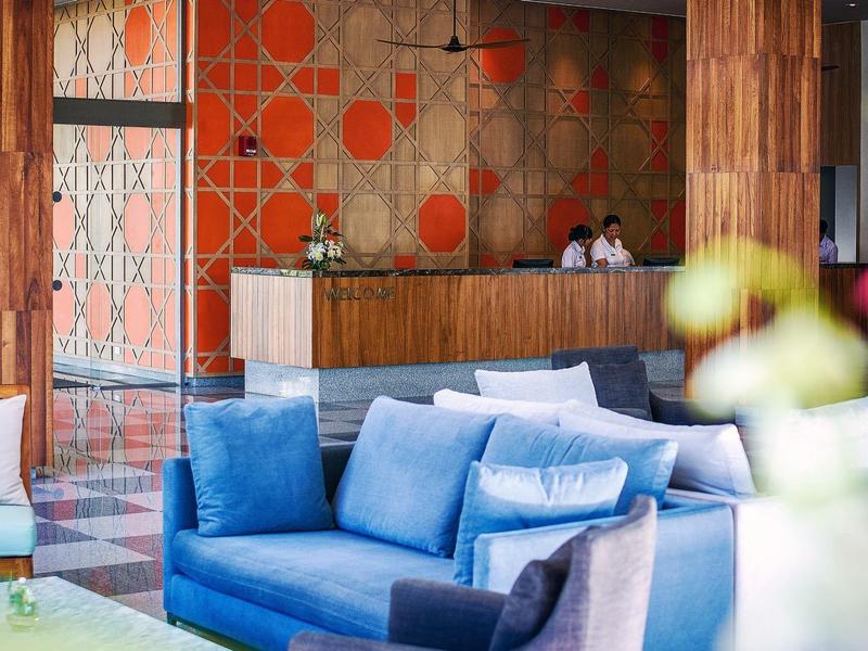 Moderne hotellobby met blauwe banken en licht hout bij de receptie.