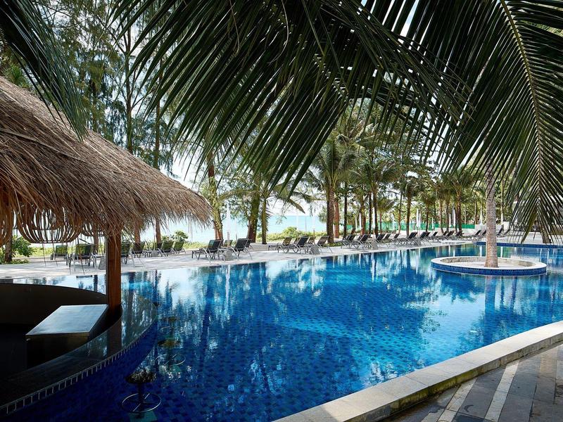 Zwembad met palmbomen en rieten dak in tropisch resort