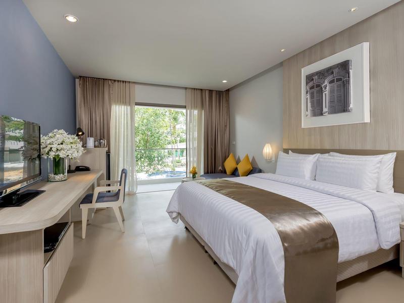 Moderne hotelkamer met groot bed, bureau en uitzicht op een terras.