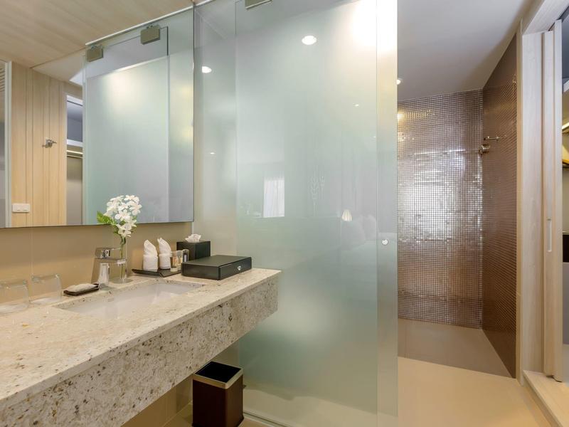 Moderne hotelbadkamer met grote spiegel en matte glazen douche.