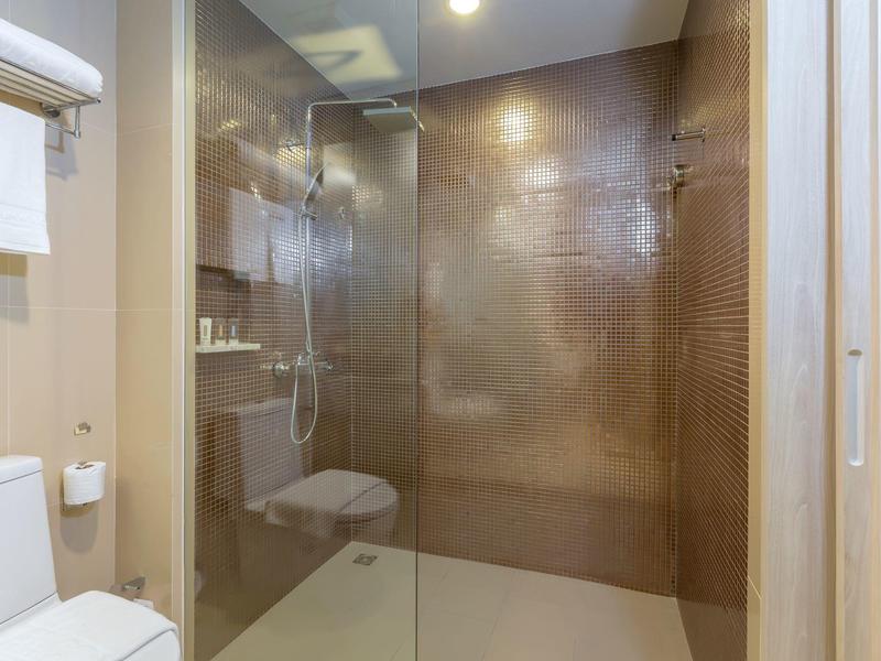 Moderne badkamer met inloopdouche, glazen afscheiding en wit toilet.