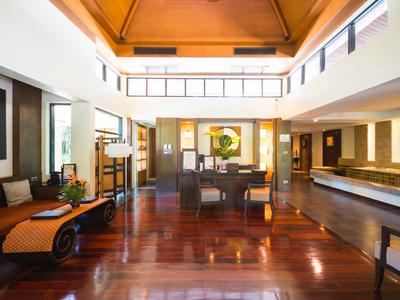 Elegante hotellobby met gepolijste houten vloeren, moderne zithoeken en veel natuurlijk licht.