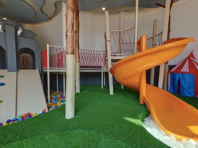 Overdekt speelgebied met kleurrijke klim- en glijbaan speelplaats op groene tapijtvloer.