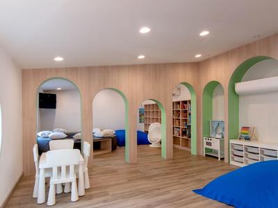 Speel- en slaapgedeelte voor kinderen met houten vloeren, kleurrijk meubilair en afgeronde deuropeningen.