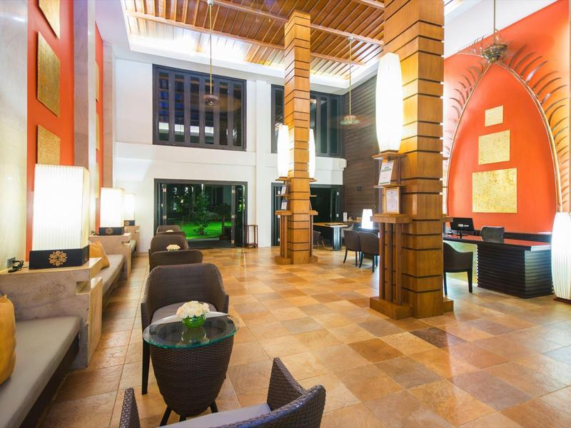 Lichte en moderne hotel lobby met houten zuilen, zitgedeeltes en warme kleuren.