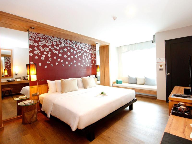 Modern hotelkamer met groot bed, decoratieve wand en zitplek bij het raam.