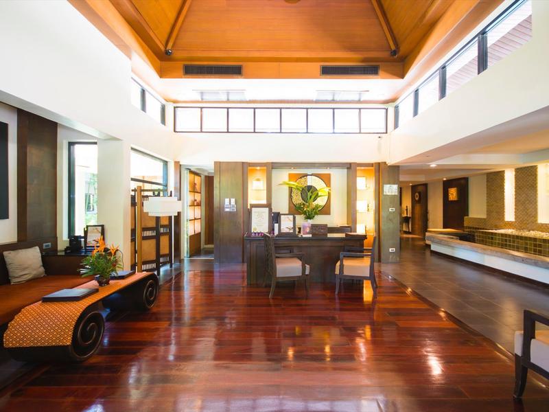 Elegante hotellobby met gepolijste houten vloeren, moderne zithoeken en veel natuurlijk licht.