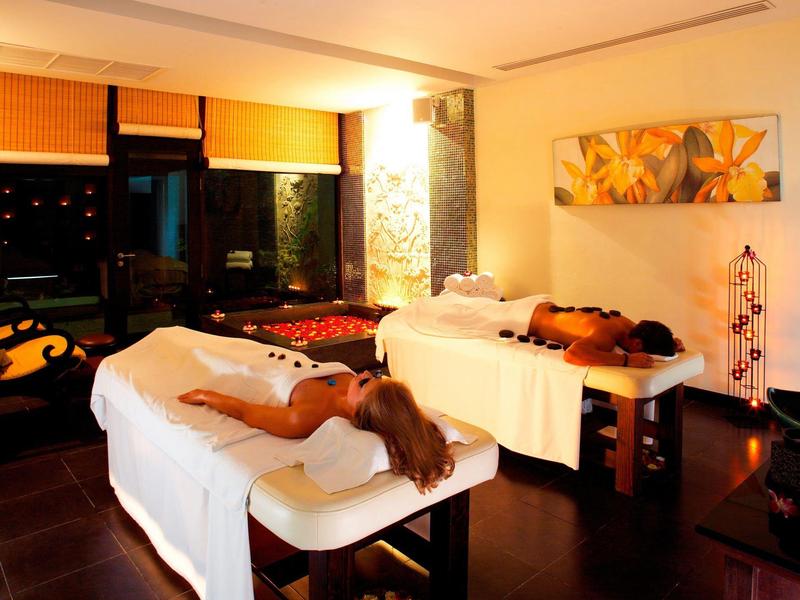 Twee mensen ontspannen op massagetafels in een warm verlichte spa-ruimte.