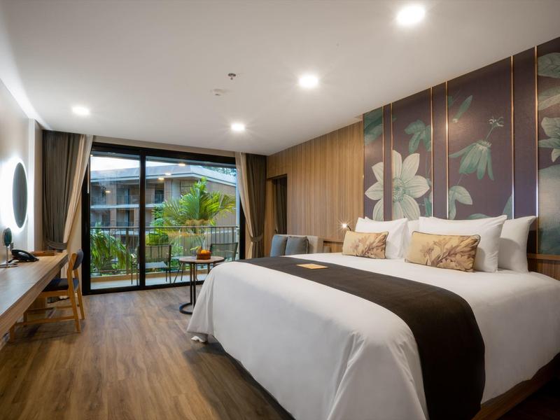 Moderne hotelkamer met groot bed, houten vloer en uitzicht op de tuin.