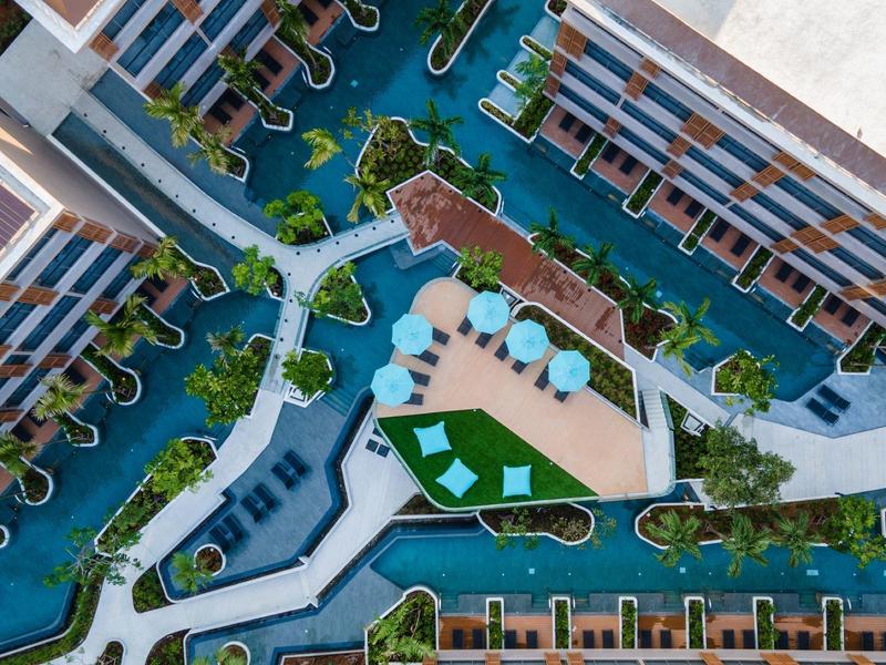 Luchtfoto van een hotelresort met zwembaden, ligstoelen en parasols.