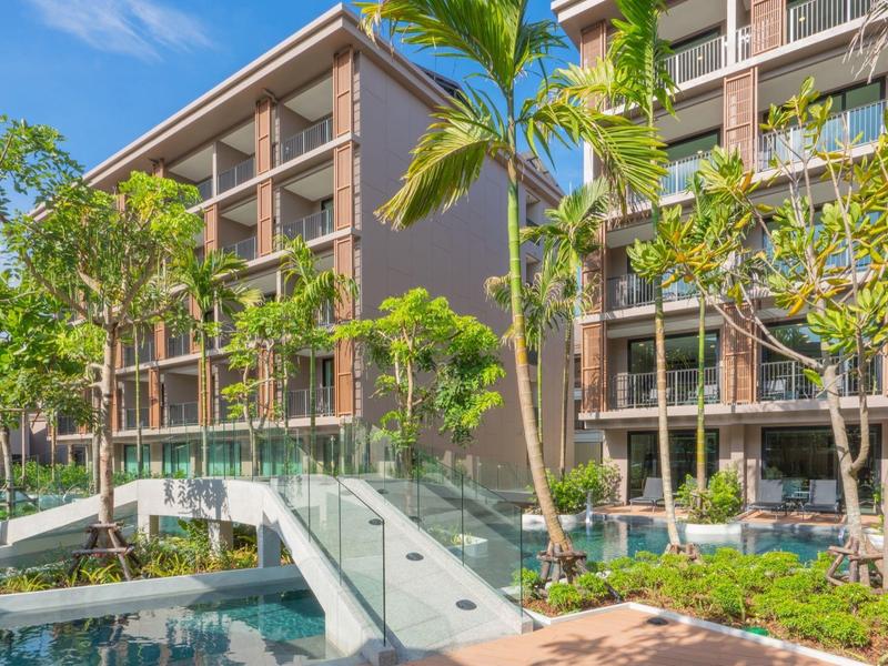 Modern hotelgebouw met glazen brug over een zwembad en tropische planten