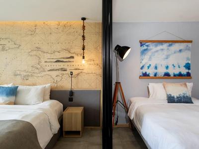 Two single beds in a modern hotel room with nautical decor and soft lighting.