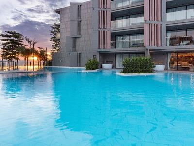 Moderner Hotelpool bei Sonnenuntergang mit Blick auf Palmen und Meer