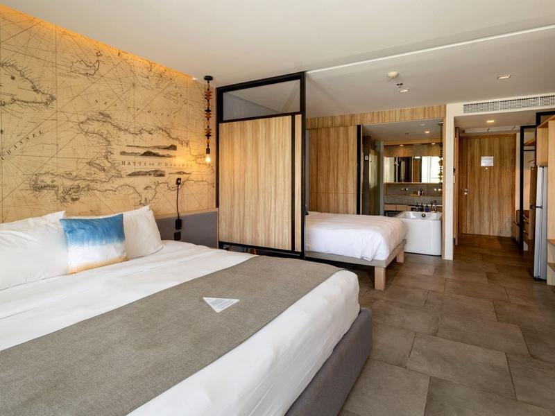 Modern hotel room with two beds and elegant wood paneling.