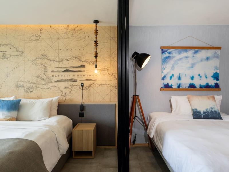 Two single beds in a modern hotel room with nautical decor and soft lighting.