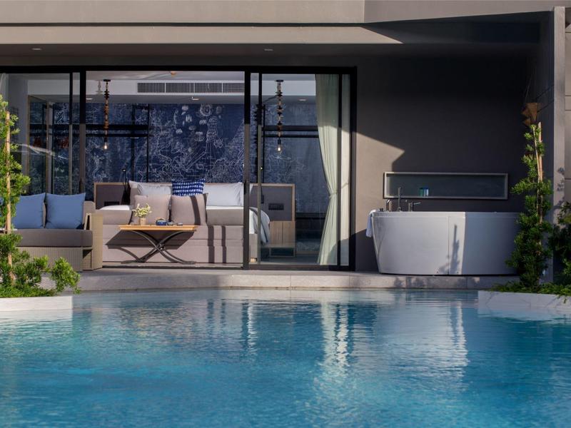 Modern outdoor area with swimming pool, seating area, and freestanding bathtub by glass facade.