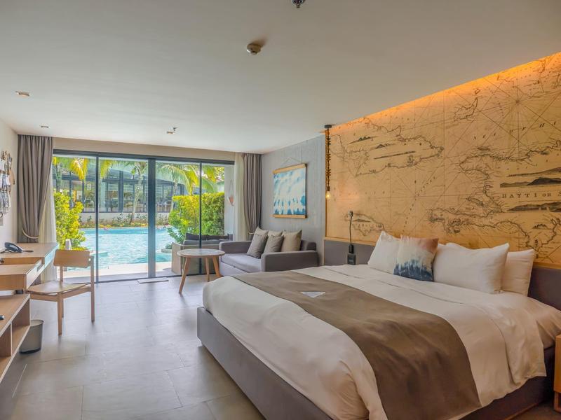 Cozy hotel room with large bed, sofa, and view of outdoor pool.