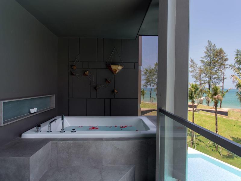 Modern hot tub on balcony overlooking sea and palm trees on a sunny day.