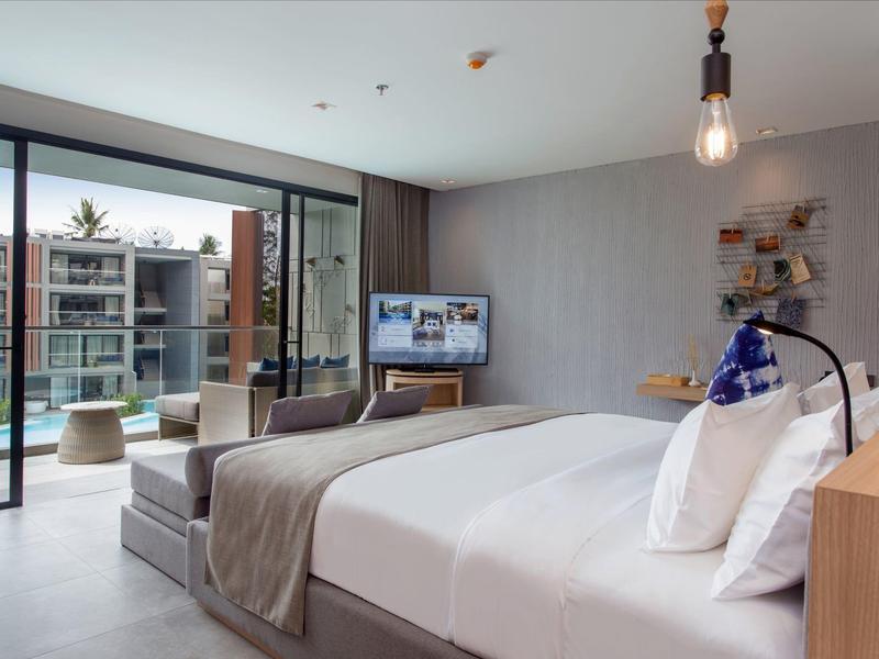 Modern hotel room with large bed, TV, desk, and balcony seating area.