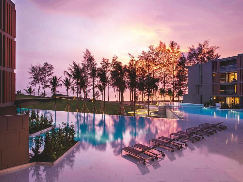 Luxury hotel pool with lounge chairs and sunset in the background