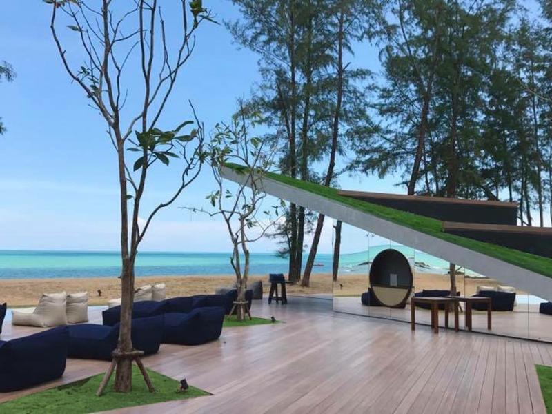Modern pool area with seating and sea view under clear blue sky.