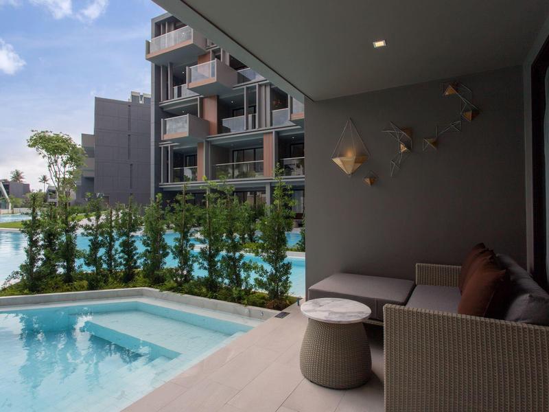 Modern hotel terrace with seating area overlooking pool and garden area.