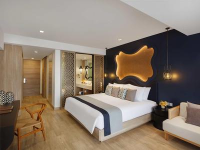 Habitación de hotel moderna con cama doble, suelo de madera y decoración de pared iluminada.
