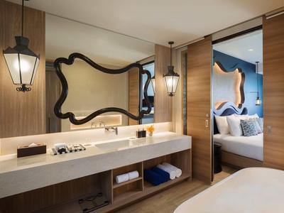 Habitación de hotel moderna con espejo grande, paredes de madera y cama doble con decoración azul en la pared.