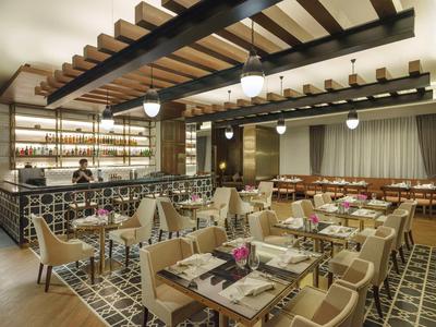 Modernes Restaurant mit Holzdecke, stilvollen Tischen und beige Stühlen in einem warm beleuchteten Raum.