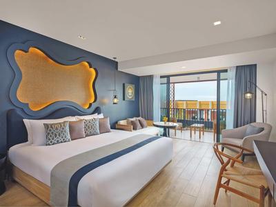 Modernes Hotelzimmer mit großem Bett, Meerblickbalkon und stilvoller Wanddekoration.