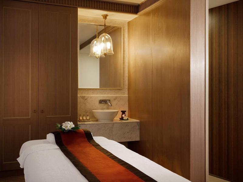 Una habitación de hotel con una cama, un tocador, revestimientos de madera y luz tenue.