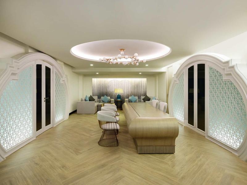 Área de espera elegante con asientos cómodos, piso de madera clara y iluminación elegante.