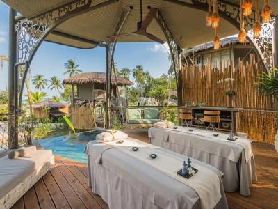 Area relax con lettini da massaggio sotto un padiglione coperto accanto a una piscina.