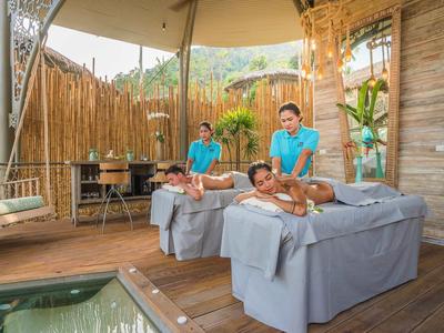 Due persone ricevono un massaggio di coppia in una spa aperta con due terapisti.