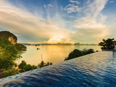 Piscina infinita con vistas a la costa y acantilados boscosos al atardecer