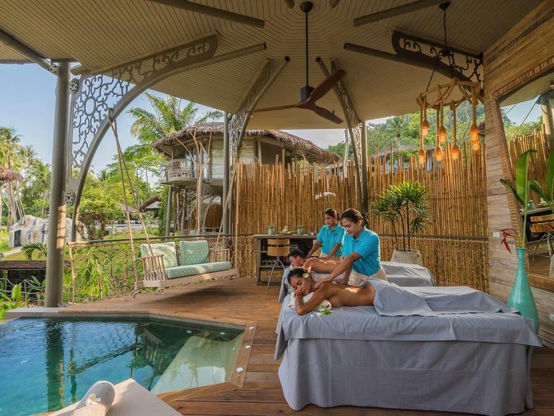 Una coppia si rilassa in un'area spa aperta con piscina e ambiente tropicale.