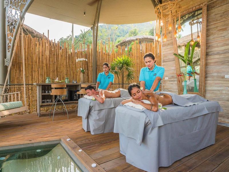 Due persone ricevono un massaggio di coppia in una spa aperta con due terapisti.