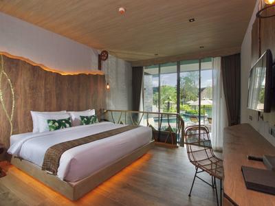 Moderní hotelový pokoj s velkou postelí, skleněnou stěnou a výhledem na balkon a hory.