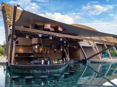 Pavillon en bois moderne avec bar ouvert et piscine extérieure sous un ciel bleu.