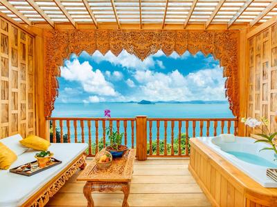 Terrazza in legno con vasca idromassaggio e vista sul mare sotto un cielo azzurro